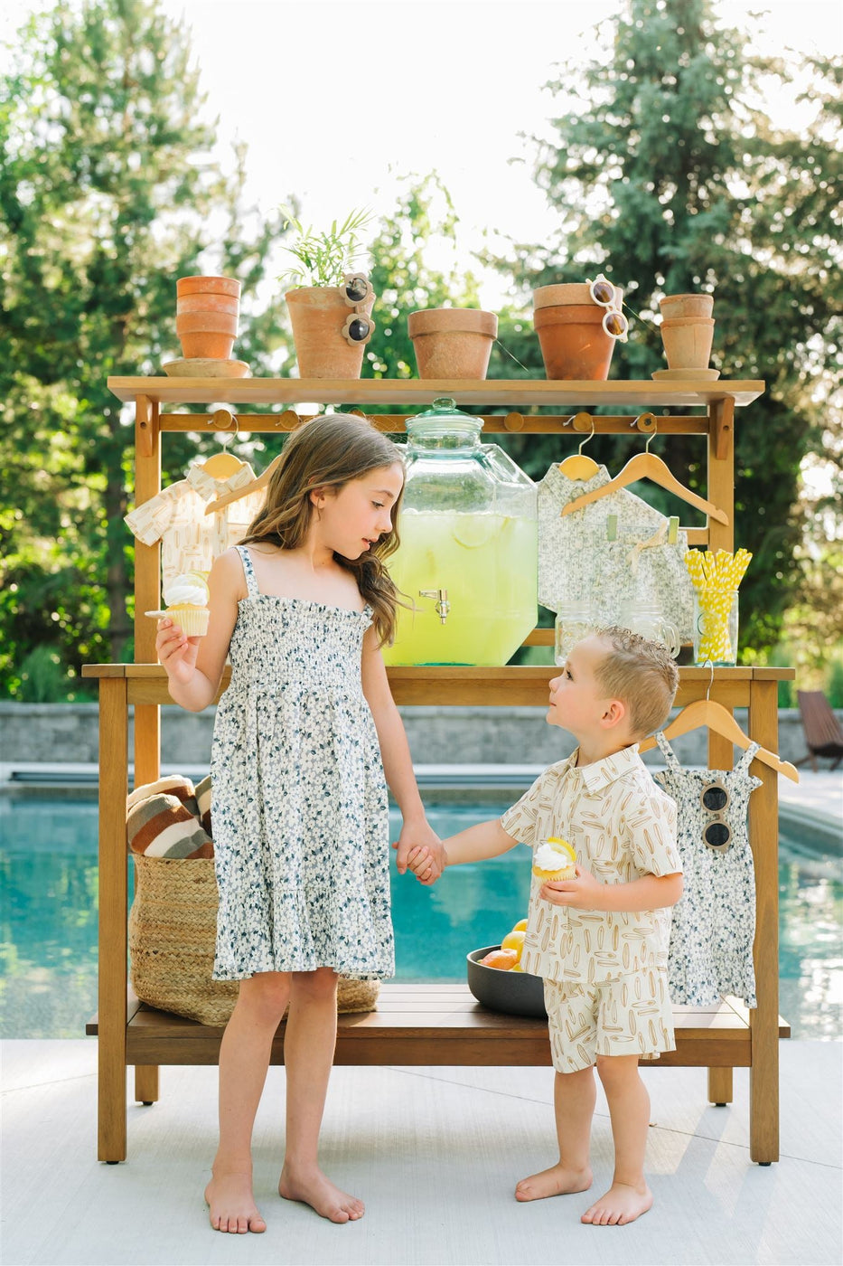 a boy and girl holding hands by a lemonade stand