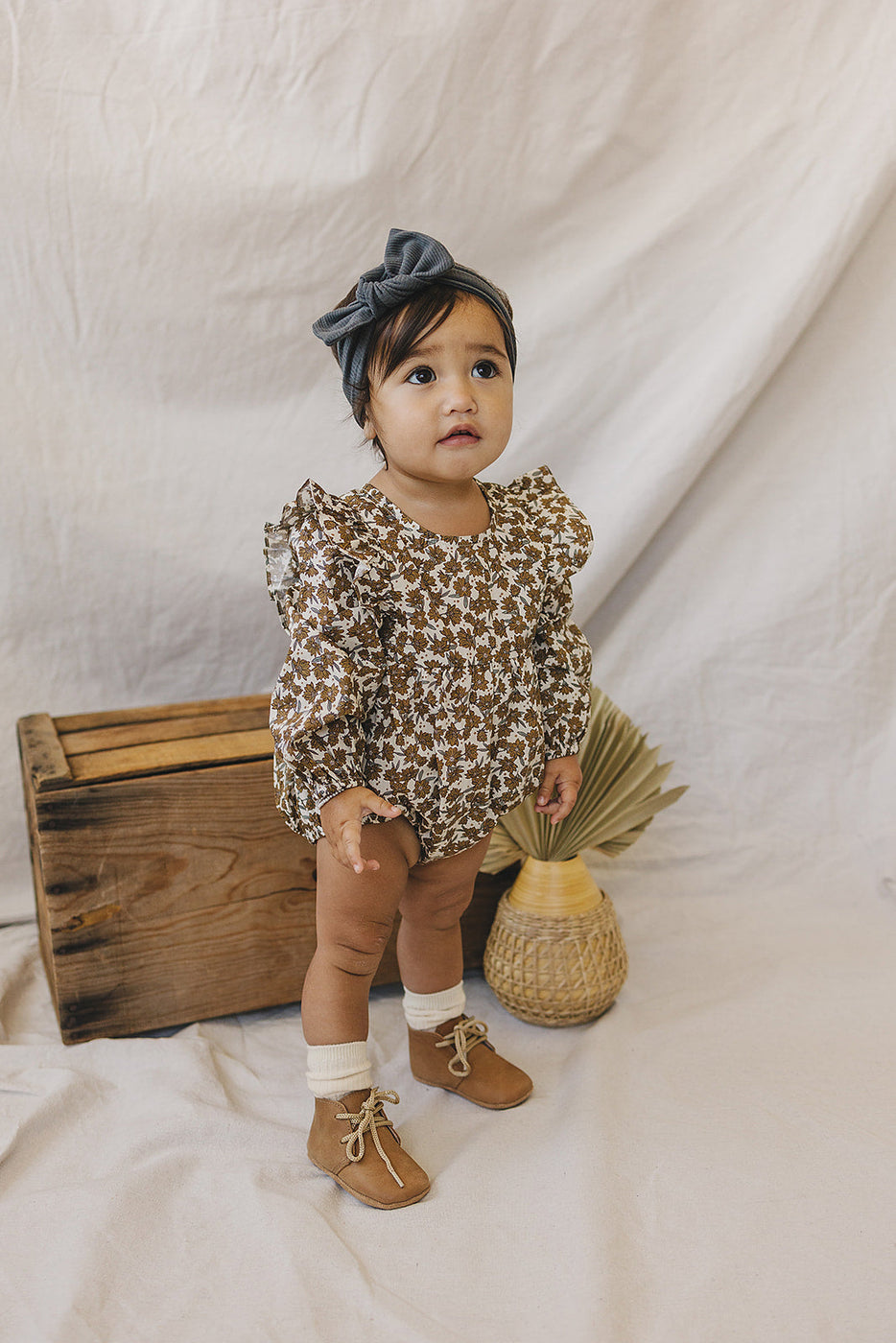 a baby standing next to a wooden box