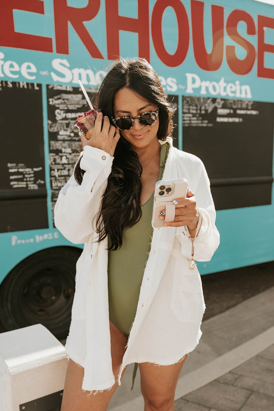 a woman in a bathing suit holding a phone and a drink