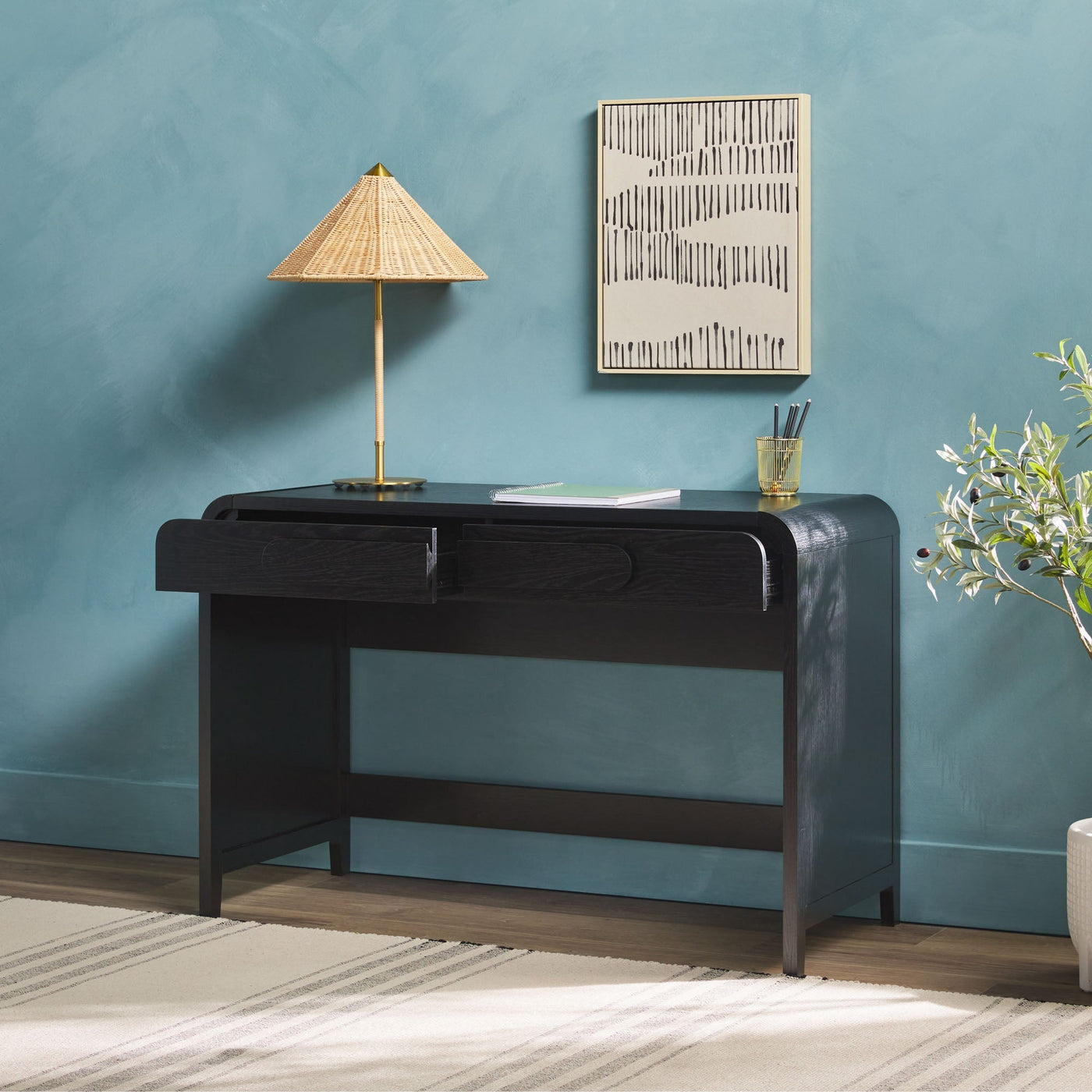 a desk with a lamp and a painting on the wall