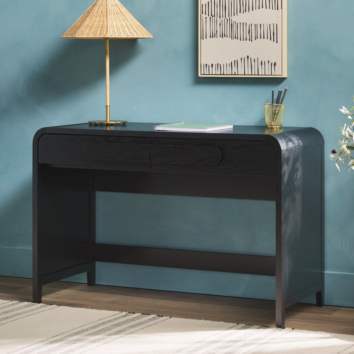 a desk with a lamp and a painting on the wall