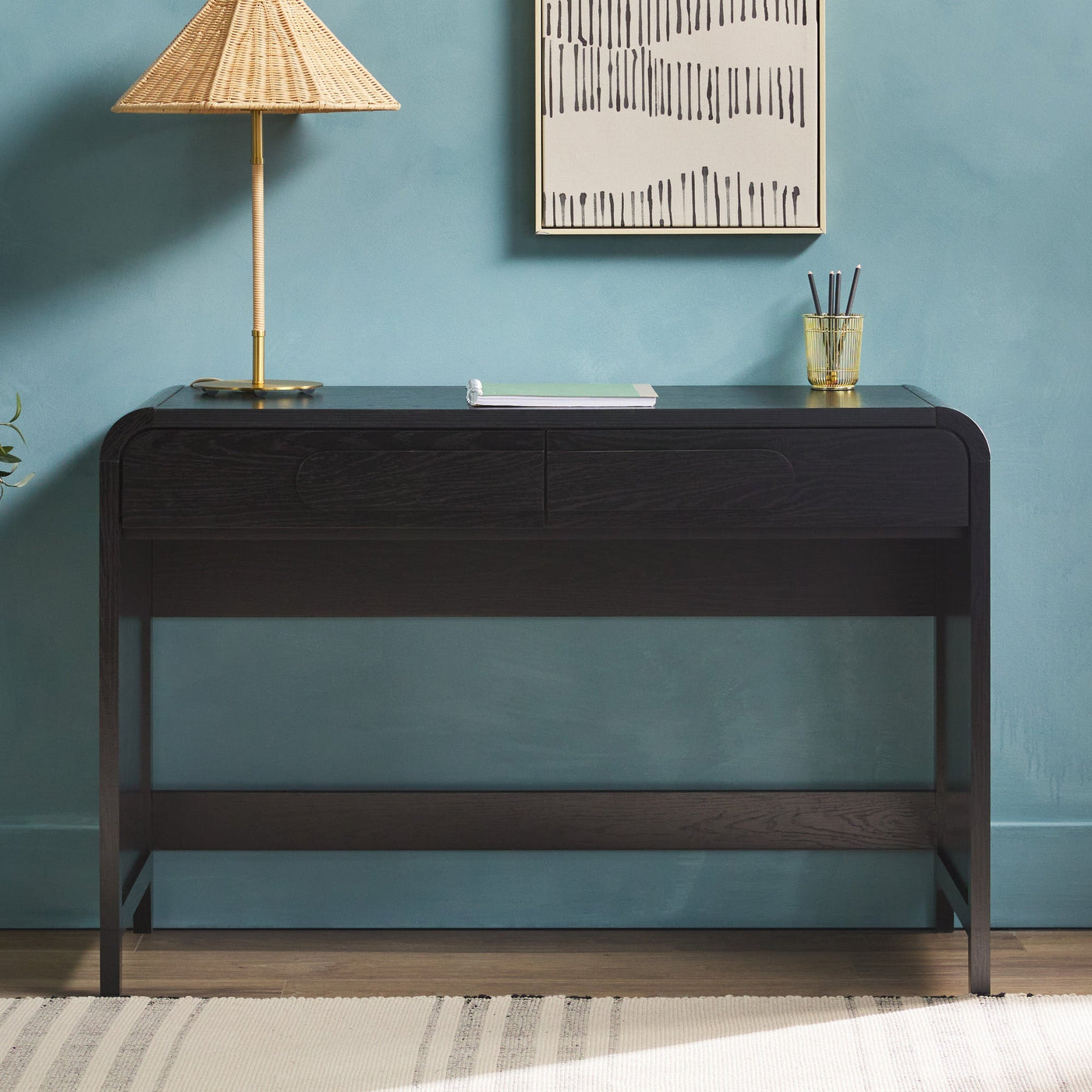 a desk with a lamp and a picture on the wall