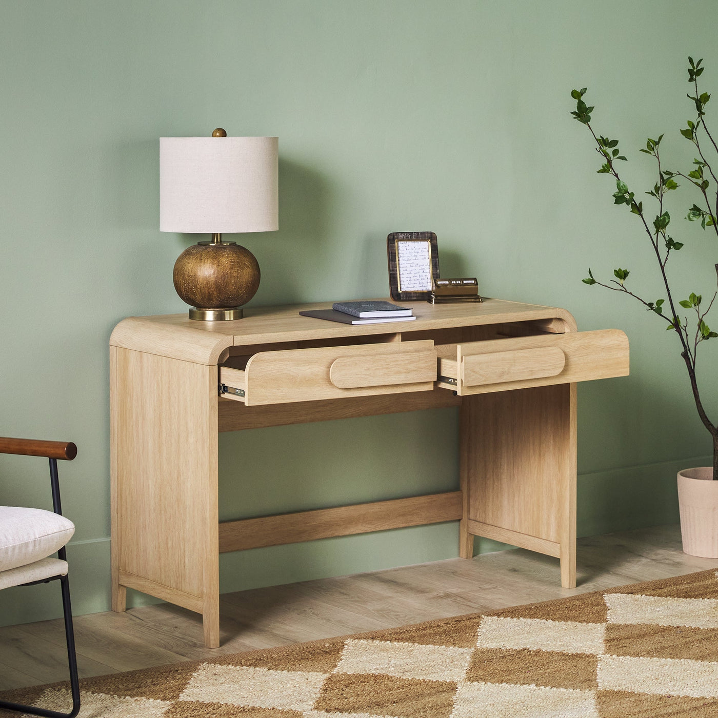 a desk with a lamp and a plant in a room