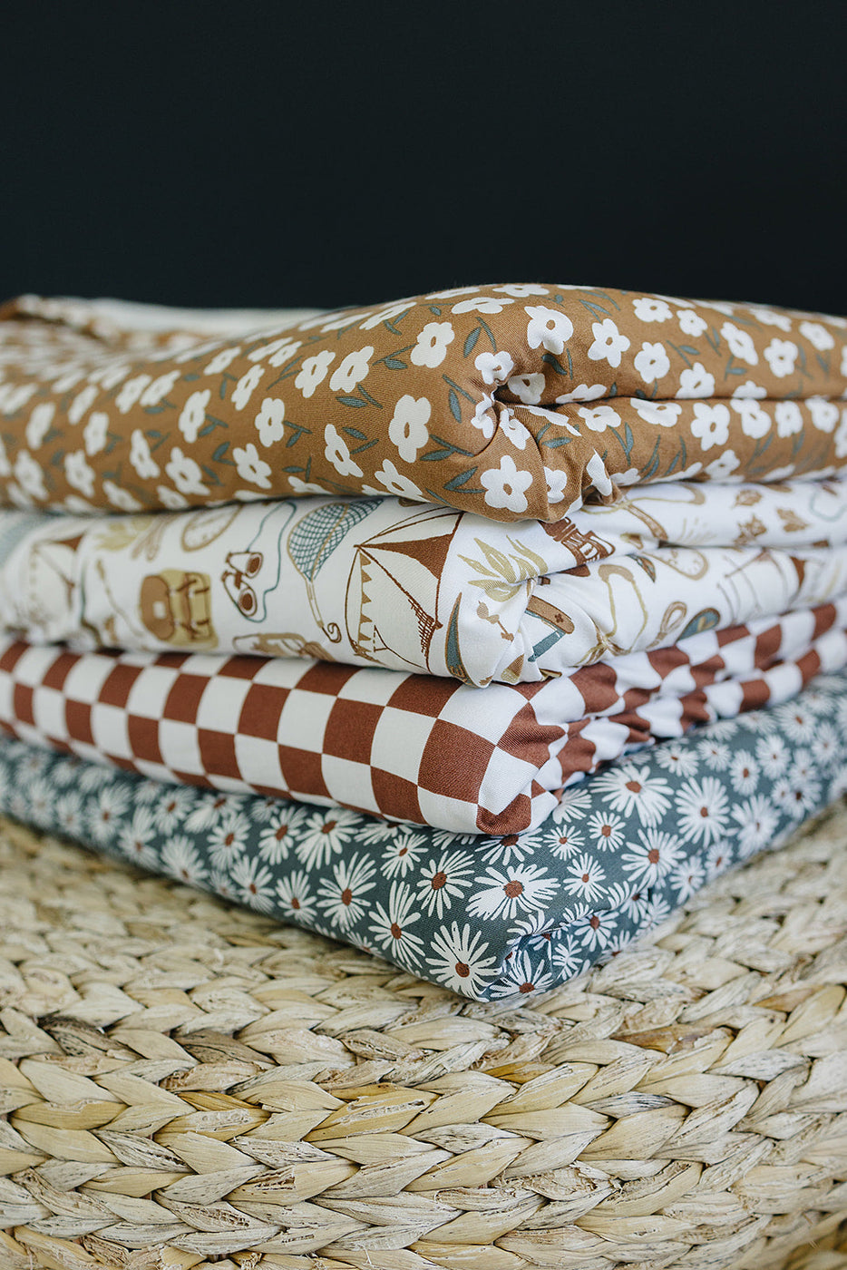 a stack of blankets on a woven mat