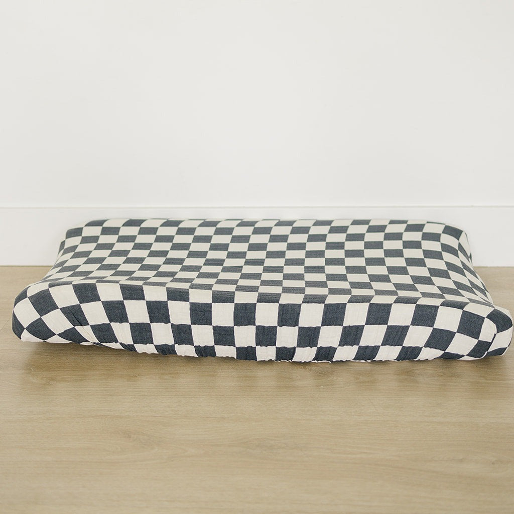 a black and white checkered pillow on a wood surface