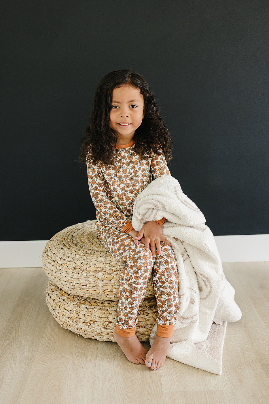 a girl sitting on a stack of wicker baskets