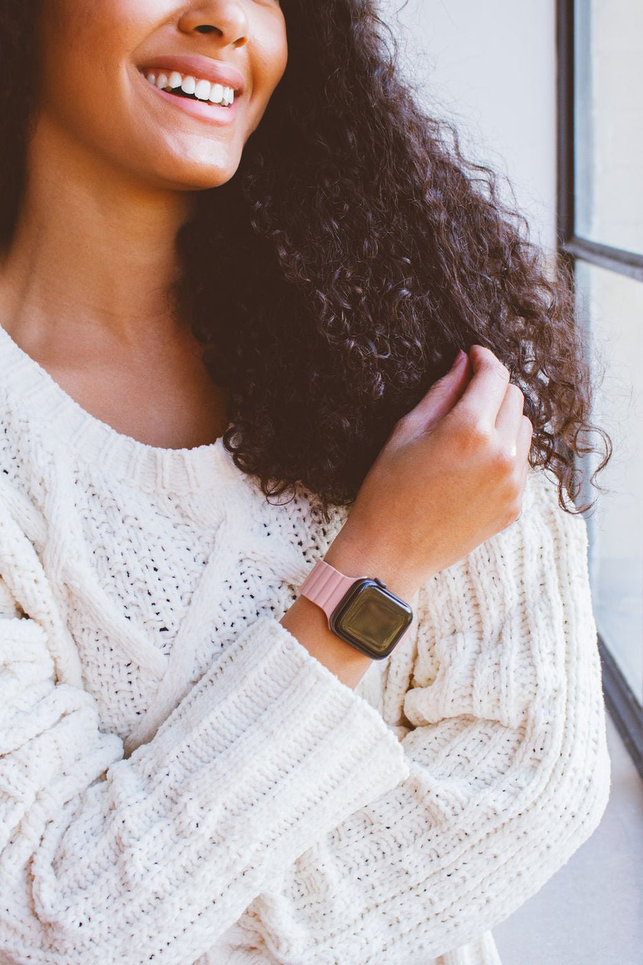 a woman wearing a white sweater and a pink watch