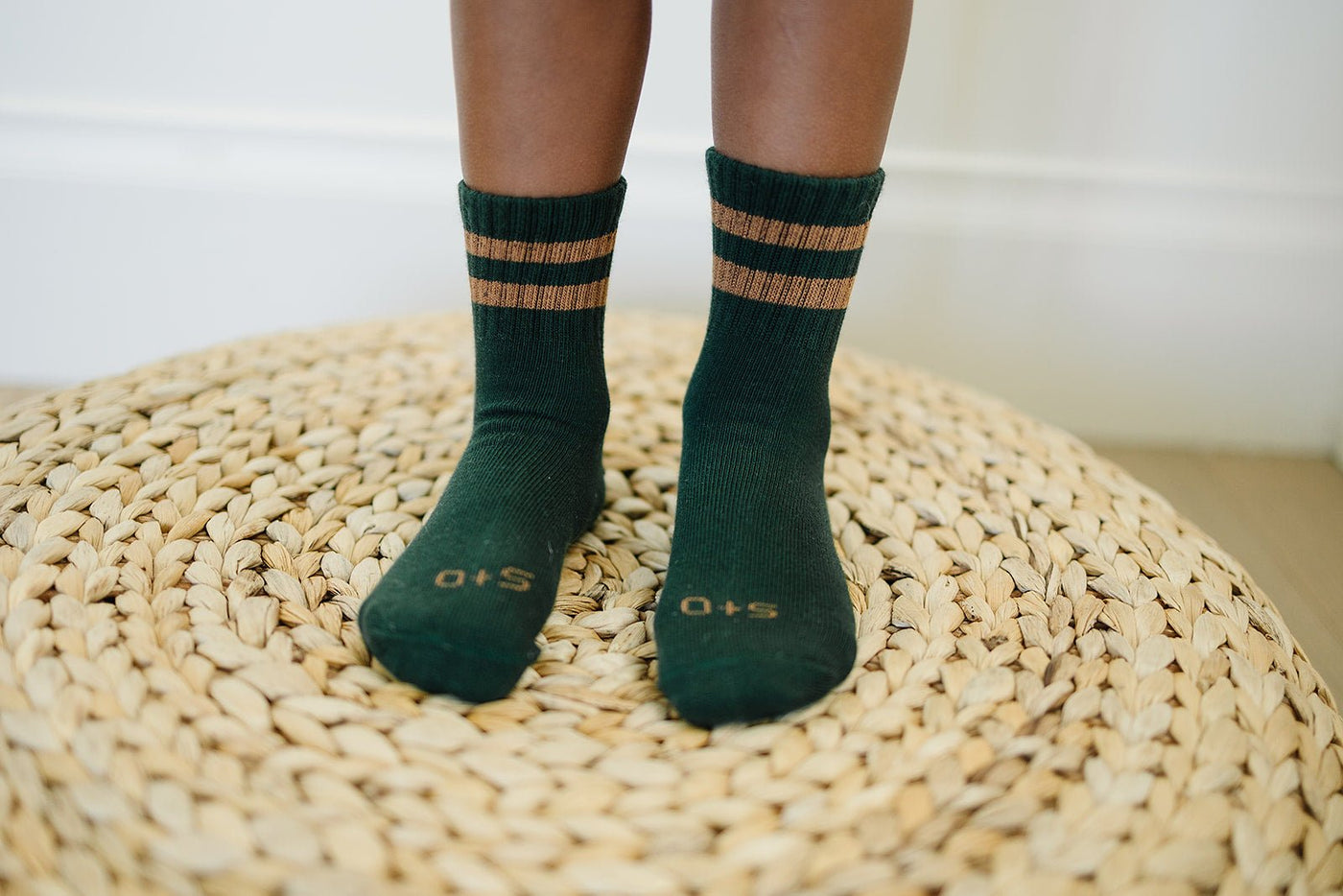 a person's feet in socks on a woven mat