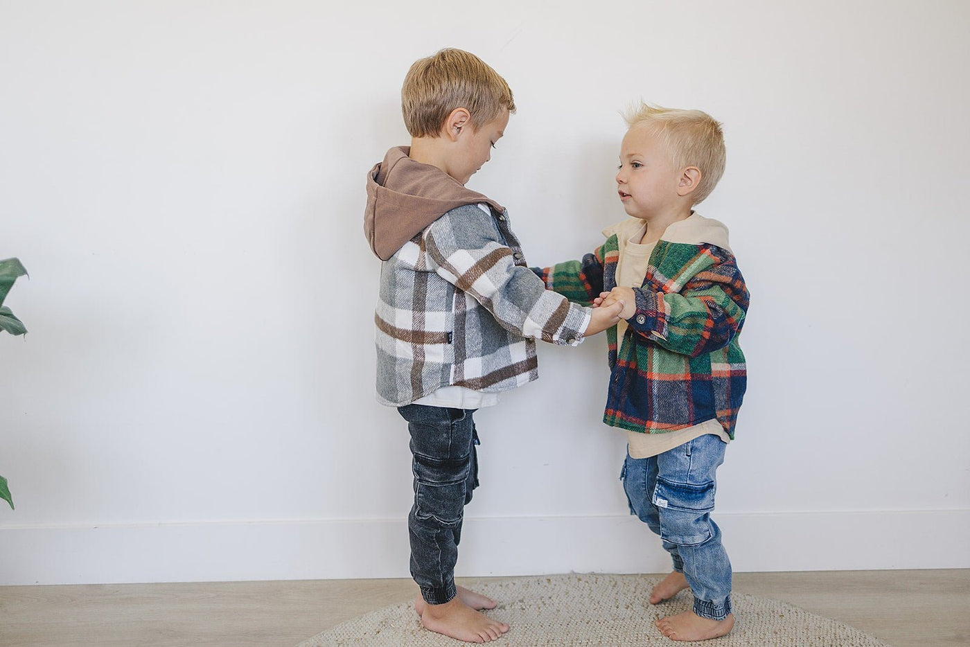 two boys holding hands and standing on carpet