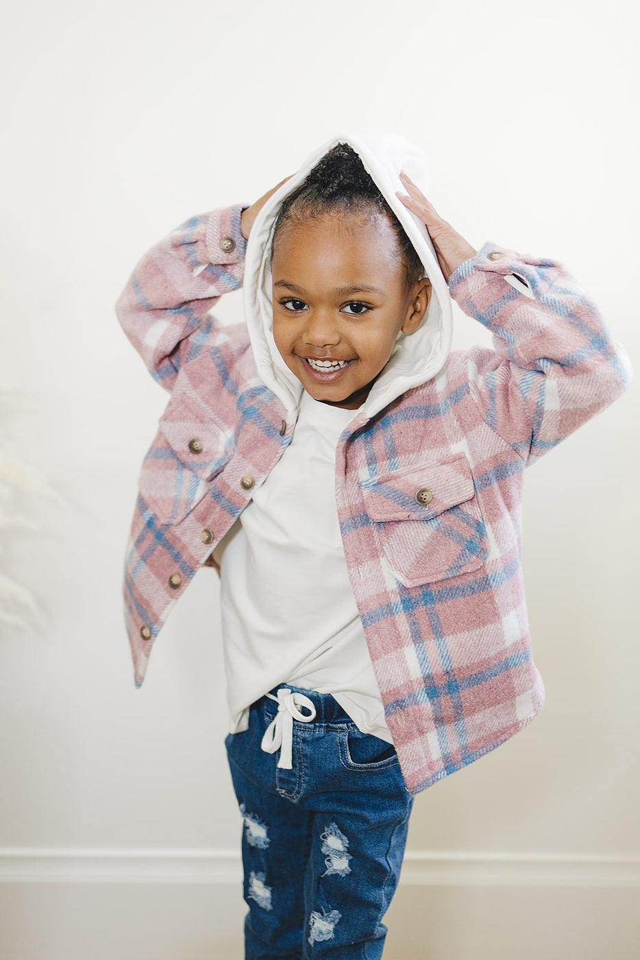 a girl wearing a pink and blue plaid jacket