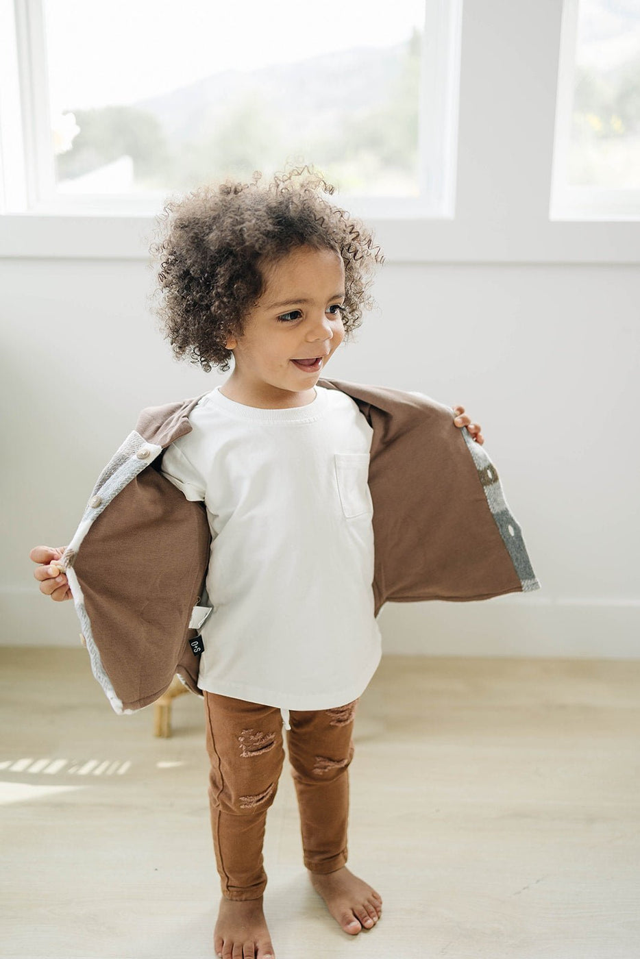 a child wearing a white shirt and brown pants