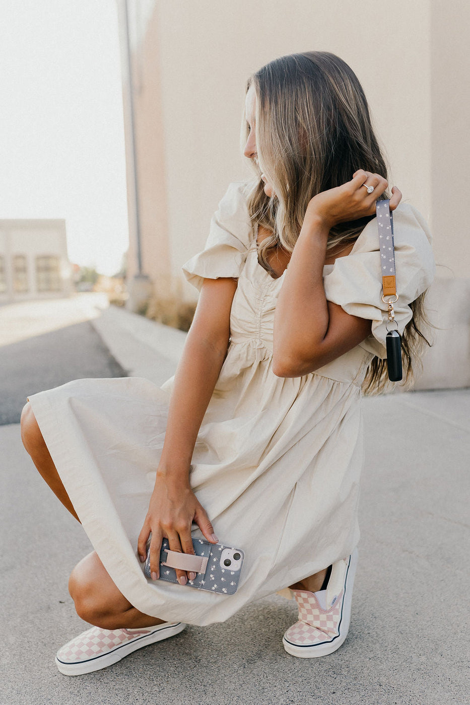 a woman in a white dress holding a phone and a phone case