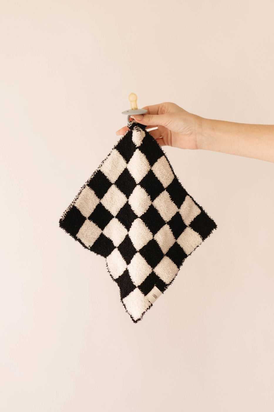 a hand holding a black and white checkered blanket