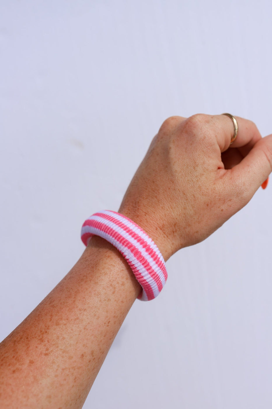 a hand with a pink and white striped wristband