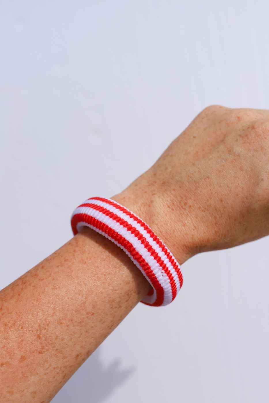 a red and white striped wristband on a person's arm