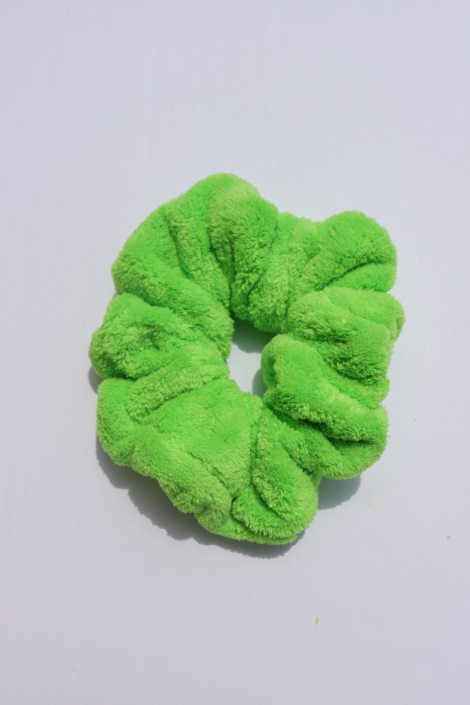 a green hair scrunchie on a white surface
