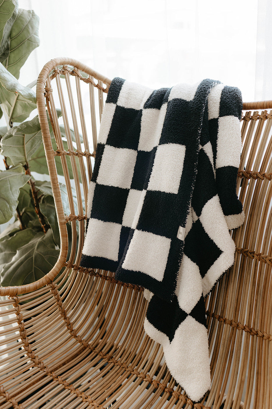 a black and white checkered blanket on a wicker chair
