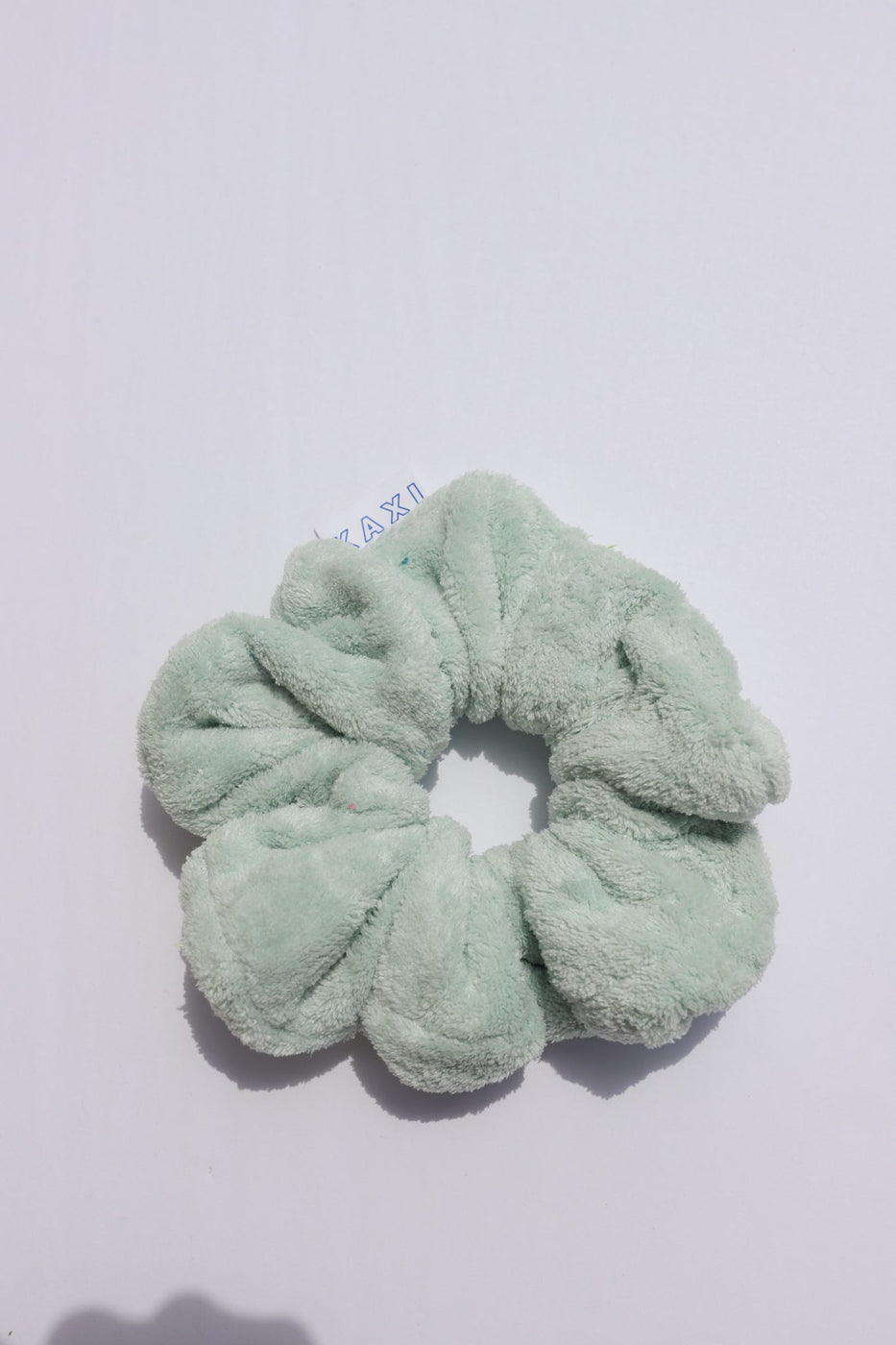 a green scrunchie on a white surface