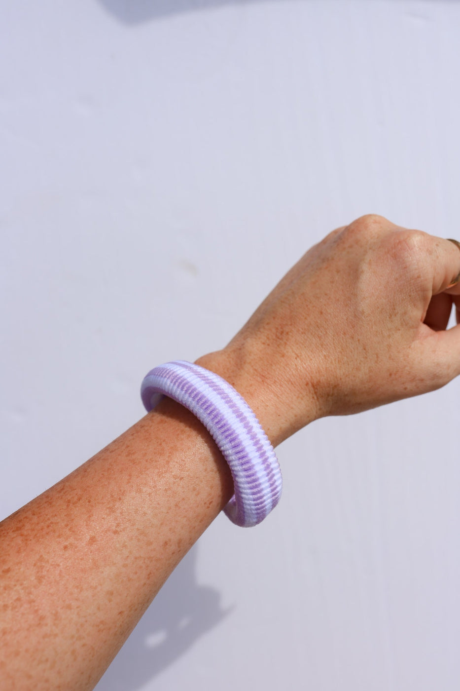 a hand with a purple and white wrist band