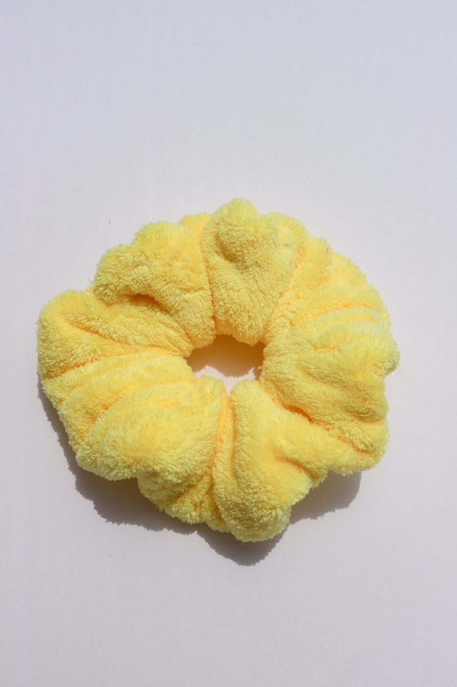 a yellow hair scrunchie on a white surface