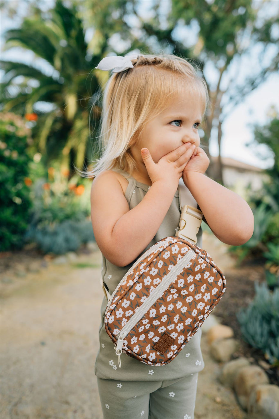 a child with a white bow on her head holding a small purse