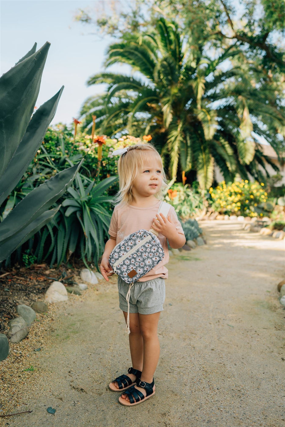 a child standing on a path with plants and flowers