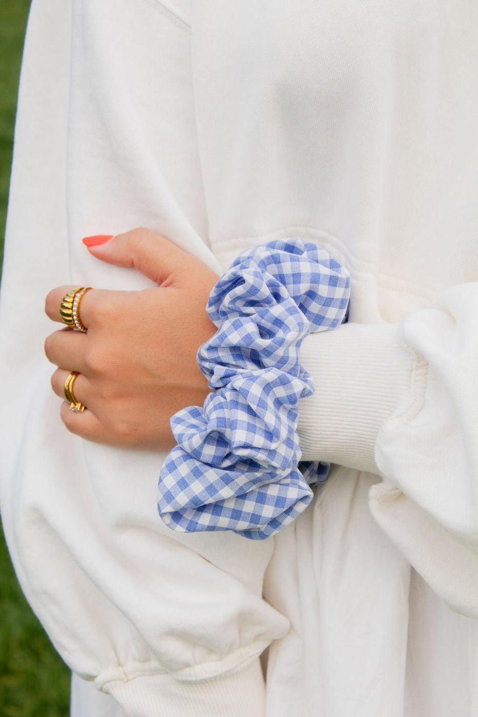 a person wearing a white sweater with a blue and white checkered scrunchie
