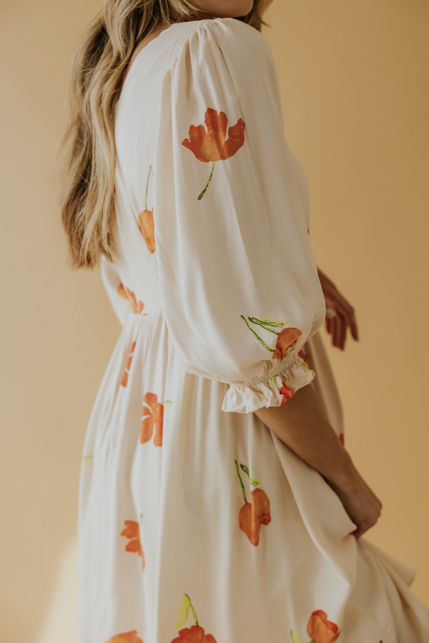 a woman wearing a white dress with orange flowers on it
