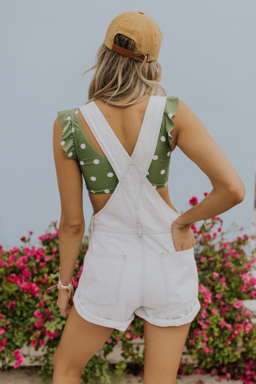 a woman in a green and white polka dot top and white overalls