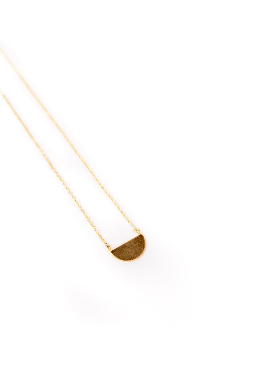 a gold necklace with a half moon pendant